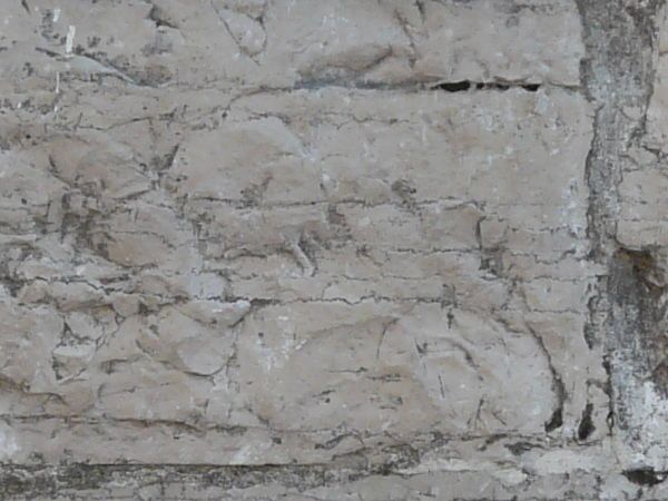 Aged white stone wall with dirt in cracks.